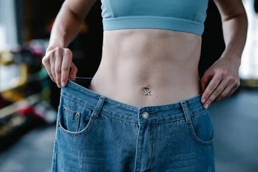 pexels-photo-7991940-7991940 A woman shows her weight loss by holding oversized jeans revealing her toned stomach.