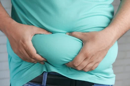 pexels-photo-9927899-9927899 Close-up of hands gripping an overweight belly, depicting body fat focus.