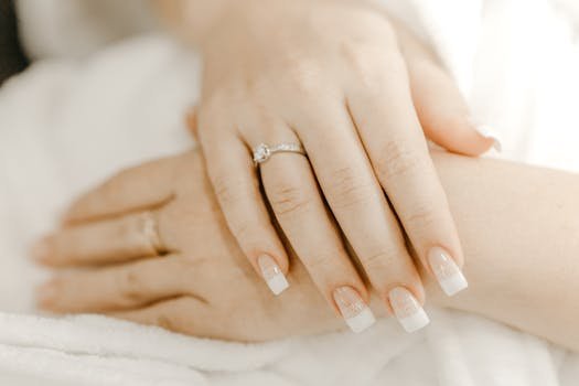 From above of hands of crop anonymous woman with classic manicure and ring with precious stone on wedding day