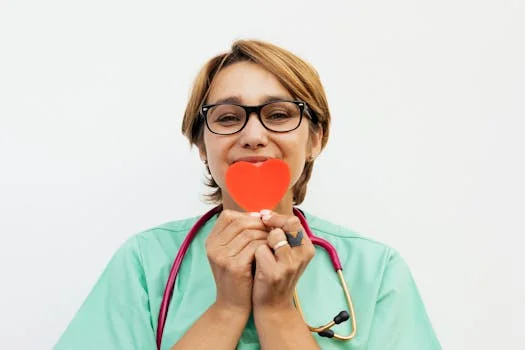 Doctor holding a red heart symbol, promoting healthcare compassion.