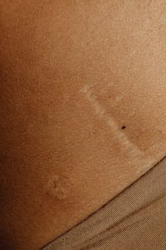 Detailed close-up shot of natural skin texture showing a scar and beauty marks.