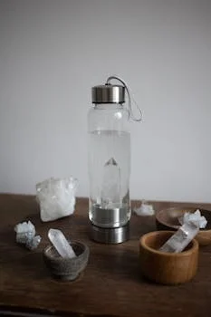 A stylish arrangement of a crystal-infused water bottle and healing crystals on a wooden table.