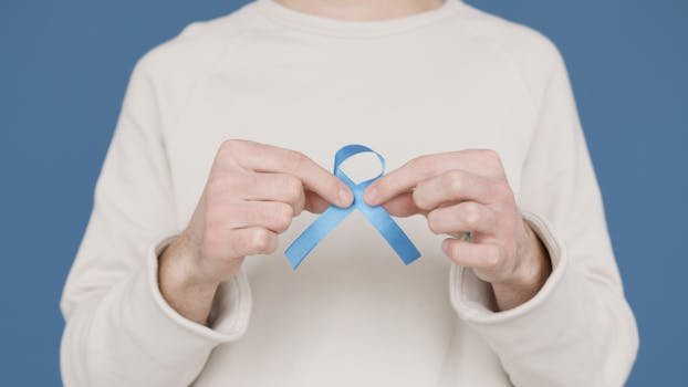 A person holding a blue awareness ribbon symbolizing support for various causes.
