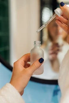 A detailed view of hands using a dropper with a cosmetic bottle, ideal for beauty product promotion.
